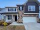 Two-story home featuring a stone facade, beige siding, black shutters, and an attached two-car garage at 1336 Weavers Trace Dr, Zebulon, NC 27597