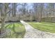 A beautifully landscaped backyard with a curved brick paver walkway leading to a wooden fence and mature trees at 1600 Patterson Grove Rd, Apex, NC 27502