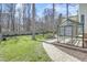 Backyard featuring a greenhouse, patio, wood fence, lawn, and tall trees at 1600 Patterson Grove Rd, Apex, NC 27502