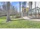 Backyard with patio, greenhouse, lush lawn, mature trees, and wood fencing at 1600 Patterson Grove Rd, Apex, NC 27502