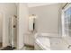 Well-lit bathroom features tiled floors, a shower, a corner tub next to a window, and a vanity with a mirror at 1600 Patterson Grove Rd, Apex, NC 27502