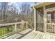 View of a home's wooden back porch leading out to a spacious backyard with mature trees and an outdoor swing set at 1600 Patterson Grove Rd, Apex, NC 27502