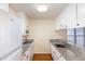 Galley kitchen featuring granite countertops, wooden floors, and white cabinets and appliances at 1614 W Cotton Gin Dr, Clayton, NC 27527