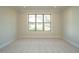 A simple bedroom with neutral carpeting and a large window with a view of the neighborhood at 205 Big Bradley Dr, Wendell, NC 27591