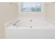 Close-up of a white soaking tub with chrome fixtures and a window above at 211 Whitney Ln, Durham, NC 27713