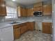 Well-lit kitchen with wood cabinetry, stainless steel microwave, white appliances and laminate floors at 4300 Mantua Way, Raleigh, NC 27604