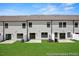 Backyard view of townhomes with a small grass area, patios, and black frame windows at 46 N District Ave # 251, Clayton, NC 27527