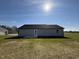 Backyard view of home with grassy lawn, blue siding, and concrete patio at 57 Faucette Dr, Selma, NC 27576