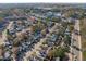 A neighborhood aerial showcases tree-lined streets, homes, and nearby lake with city skyline at 605 Stratton Way, Durham, NC 27704