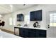 A modern kitchen featuring navy blue cabinets, stainless steel appliances, and white countertops at 606 E Pearsall St, Dunn, NC 28334