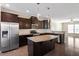 Kitchen featuring an island with bar seating, stainless steel appliances and dark wood cabinetry at 6623 Academic Ave, Raleigh, NC 27616