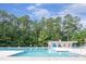 Large swimming pool surrounded by lush trees and a bath house, offering a refreshing oasis at 7025 Dayton Ridge Dr, Apex, NC 27539