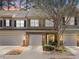 View of the townhome showing the exterior, with multiple garage doors, unique stonework, and beautiful landscaping at 107 Vickery Hill Ct, Durham, NC 27703
