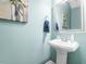 Charming powder room with pedestal sink, decorative painting, and a stylish round framed mirror at 107 Vickery Hill Ct, Durham, NC 27703