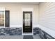 Close-up of a modern front door with decorative glass, flanked by stone accents and a sleek black shutter at 192 Springhill Ln, Garner, NC 27529