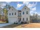 Charming two-story home featuring stone accents, a two-car garage, and a welcoming front porch with an American flag at 25 Courrone, Willow Springs, NC 27592