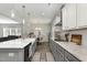 Galley kitchen featuring gray cabinets with marble countertops, and stainless appliances open to the dining room and living room at 25 Courrone, Willow Springs, NC 27592