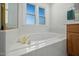 Bright bathroom featuring a large soaking tub with gold fixtures and natural light from window at 3648 Praed Pl, Fuquay Varina, NC 27526
