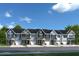 Row of townhomes with a mix of modern and traditional facades, set against a bright blue sky at 433 Grand Silo Rd, Raleigh, NC 27603