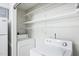 Functional laundry area with washer, dryer, and white wire shelving for storage next to a refrigerator at 4523 Hamptonshire Dr, Raleigh, NC 27613
