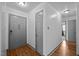 Hallway with neutral paint, wood-look floors, multiple doors, and modern fixtures at 47 Angela Way, Durham, NC 27703