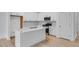Modern kitchen features all-white cabinets, a center island, and stainless steel appliances at 52 Shay St, Angier, NC 27501
