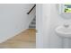 Hallway with light wood flooring and a powder room with a pedestal sink at 52 Shay St, Angier, NC 27501
