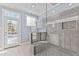 Modern bathroom with glass-enclosed shower, tile walls, and view of backyard and pool at 5317 Chimney Swift Dr, Wake Forest, NC 27587