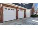 This garage has brick walls, white garage doors with windows, and hanging lanterns at 5317 Chimney Swift Dr, Wake Forest, NC 27587