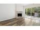 Well-lit living room featuring a brick fireplace, wood floors, and access to the outdoors at 5840 Branchwood Rd, Raleigh, NC 27609