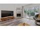 Bright living room featuring a brick fireplace, sliding glass doors, and modern wood flooring at 5840 Branchwood Rd, Raleigh, NC 27609
