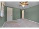 Spacious bedroom with green walls, plush carpet, closet, and a fan at 6605 Pearces Rd, Louisburg, NC 27549