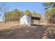 Storage shed in an open area with a white exterior and shaded lean-to at 6605 Pearces Rd, Louisburg, NC 27549
