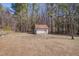 Shed with white siding and a rusted metal roof in a wooded back yard at 6605 Pearces Rd, Louisburg, NC 27549
