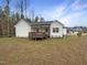View of the home's backyard with a wooden deck and spacious lawn, surrounded by trees at 95 Cinnamon Teal Way, Youngsville, NC 27596