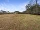 A large grassy and treed yard is surrounded by a fence and neighborhood homes at 95 Cinnamon Teal Way, Youngsville, NC 27596