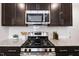 Close up of gas range stove and microwave with dark wood cabinets and granite countertops at 1010 Sora Way, Durham, NC 27703