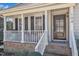 Charming front porch with brick base, white railings, seating, and a beautiful dark wood front door at 104 E Seve Ct, Morrisville, NC 27560