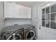 A laundry room with front load washer and dryer, overhead cabinets, and tile backsplash at 115 Ripplewater Ln, Cary, NC 27518
