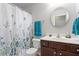 Bathroom featuring a round mirror, white shower curtain and dark wooden vanity at 127 Lakemont Dr, Clayton, NC 27520