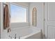 Soaking bathtub next to the window with blind, and decorative arched window pane at 127 Lakemont Dr, Clayton, NC 27520