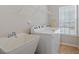 Laundry room with white appliances, wash sink, and wire shelving at 127 Lakemont Dr, Clayton, NC 27520