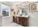Well-lit bathroom features a double vanity with dark wood cabinets, a large mirror, and natural light from a window at 13 Piccadilly Ct, Durham, NC 27713