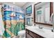 Charming bathroom includes colorful shower curtain, decorative artwork, and wood framed mirror at 13 Piccadilly Ct, Durham, NC 27713