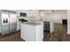 Modern kitchen with stainless steel appliances, center island, and open view to the living room with fireplace at 132 Paper Birch Way, Fuquay Varina, NC 27526