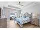 Spacious bedroom with a tray ceiling, ceiling fan, wood floors, and sliding glass door at 1727 Pinecliff Ct, Fuquay Varina, NC 27526