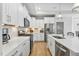 Bright kitchen featuring white cabinets, stainless steel appliances, quartz countertops, and wood-look flooring at 1727 Pinecliff Ct, Fuquay Varina, NC 27526