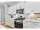 Modern kitchen with white cabinets, a stove and decorative backsplash at 1727 Pinecliff Ct, Fuquay Varina, NC 27526