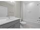 Bathroom featuring a tub with white subway tile surround, gray vanity, and silver fixtures at 2321 Calluna Ct, Fuquay Varina, NC 27526