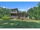 View of the backyard with covered porch, lower level patio, and lots of green grass at 295 Cedar Rock Trl, Fuquay Varina, NC 27526